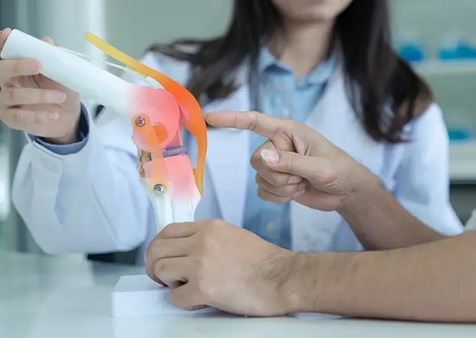 Doctor explain knee pain with model to patient