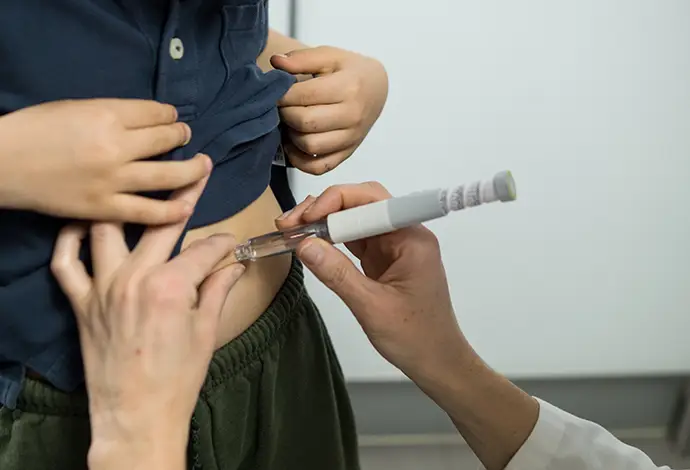 physician injecting a patient in the stomach using a modern medical pen