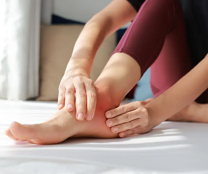 Woman massaging her painful foot with red highlight on sole and ankle