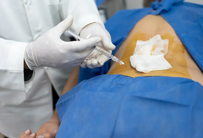 doctor administering an injection to a senior patient's spine as a treatment for sciatica pain