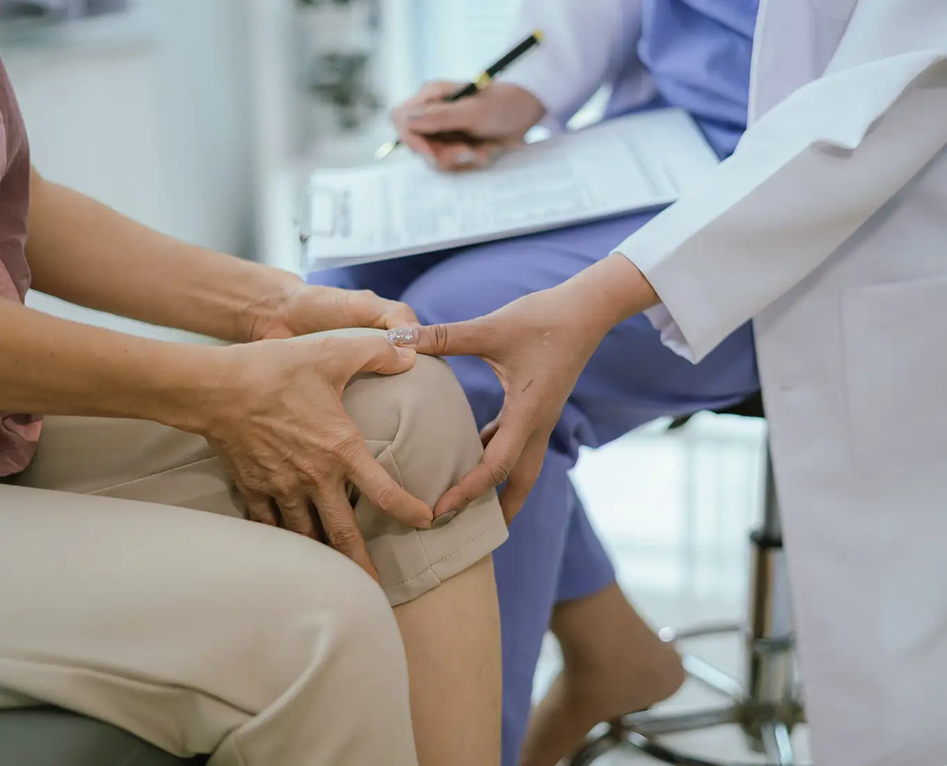 Healthcare provider examining a patient’s knee during a pain treatment consultation.