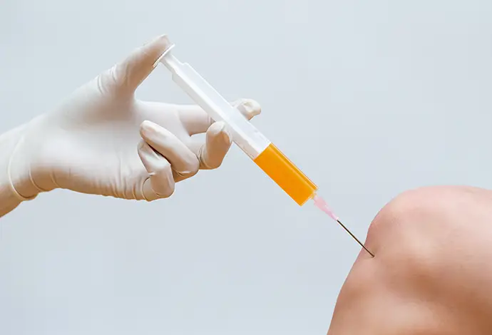 Doctor doing stem cell therapy on a knee with platelet-rich plasma injection